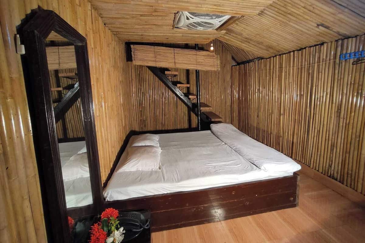 A wooden room with a bed, a mirror, and a staircase.