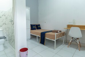 Een kleine, schone kamer met een bed, een bureau en een stoel.