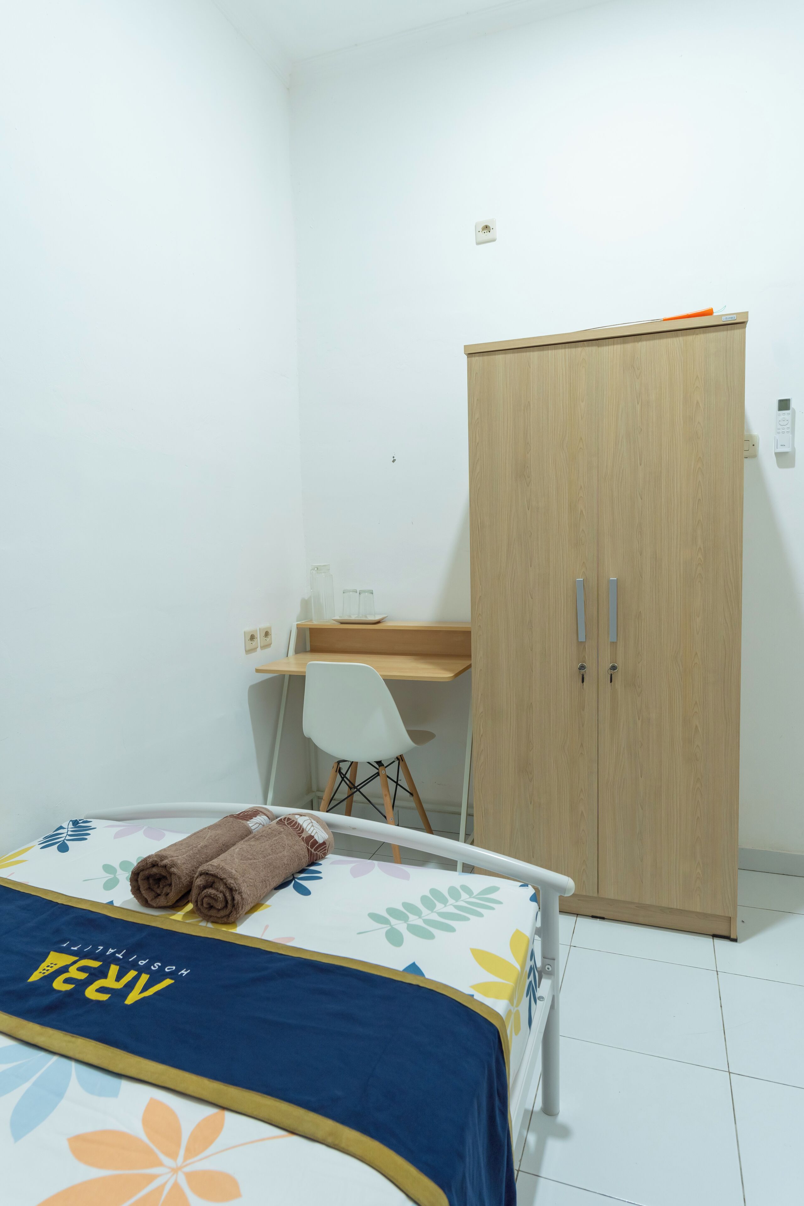 Ein kleines, sauberes Zimmer mit einem Bett, einem Schreibtisch und einem Kleiderschrank.