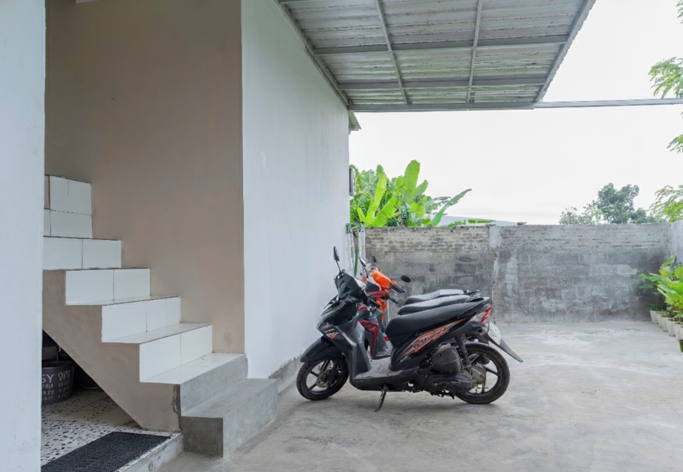 A concrete staircase leading to a covered area with a parked scooter.