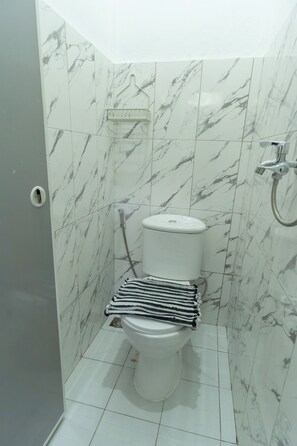 Een badkamer met een toilet, een douche en een handdoekrek.