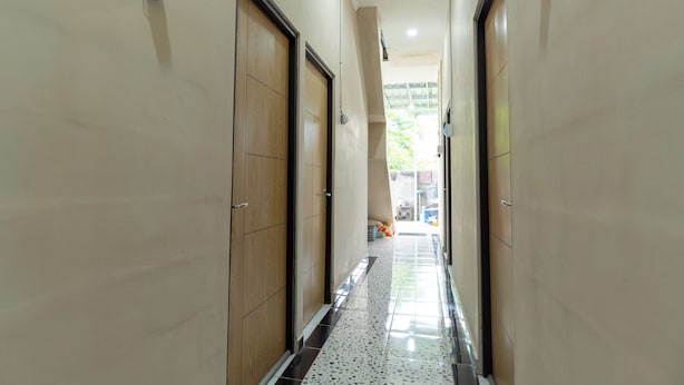 A hallway with wooden doors and a tiled floor. - ELBA Guesthouse Near UNNES by ARBA (Semarang)