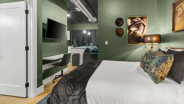 Un dormitorio moderno con cama, escritorio y televisión.