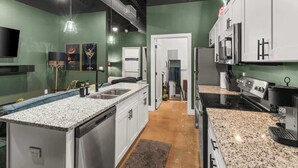 Una cocina moderna con encimeras de granito, electrodomésticos de acero inoxidable y una isla central.