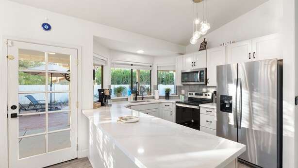 Een moderne keuken met witte kastjes, roestvrijstalen apparatuur en een groot eiland.