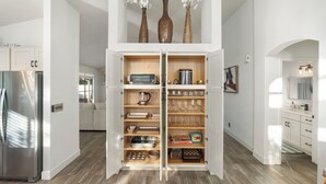 Een moderne keuken met een inbouwvoorraadkast, roestvrijstalen apparatuur en een houten vloer.