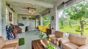 A spacious living area with a sofa, a coffee table, and a dining area with yellow chairs. - Padma Luxury Resort MawaGhat Dhaka (Louhajang)