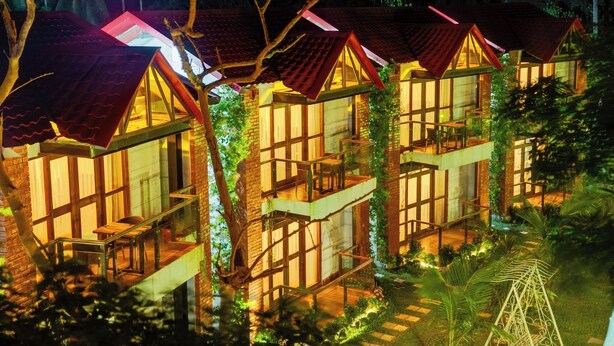 A row of modern, multi-story buildings with large windows and balconies, surrounded by lush greenery. - Padma Luxury Resort MawaGhat Dhaka (Louhajang)