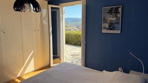 A bedroom with a bed, a wardrobe, a door leading to a balcony, and a framed picture on the wall.