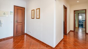 Un passadís ampli amb sòl de rajola, portes de fusta i quadres emmarcats a la paret.