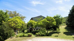 Una casa con un jardín amplio, rodeada de árboles y un cielo despejado.