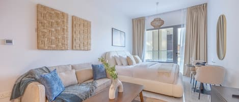 Una sala moderna con sofá, una mesa de centro y una zona de comedor con una silla y mesa.