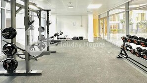 Ein Fitnessraum mit Gewichthebergeräten, großen Fenstern und Blick ins Freie.