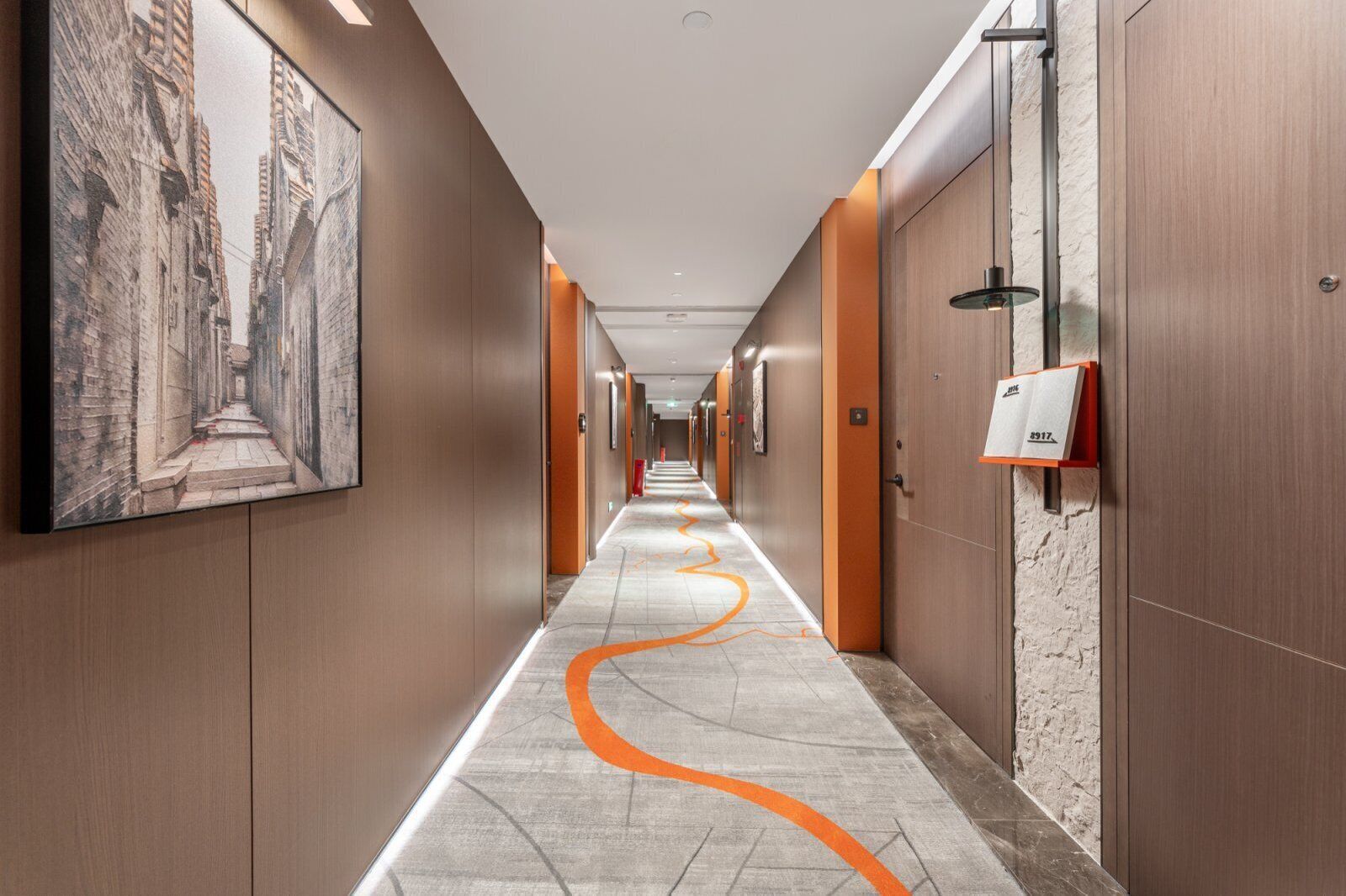A modern hotel corridor with wooden walls, a marble floor, and a long hallway with doors on one side.