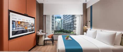 Una habitación de hotel moderna con una cama grande, un escritorio y un televisor montado en la pared.