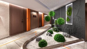 Un moderno vestíbulo de hotel con una fuente central, paredes de madera y piedra, y un techo con luces integradas.