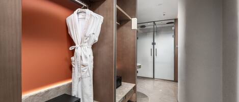 Une salle de bain moderne avec un peignoir accroché au mur, un four à micro-ondes et une cabine de douche en verre.