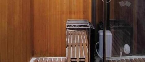 A wooden-paneled bathroom with a shower area, a small wooden stool, and a glass shower door.