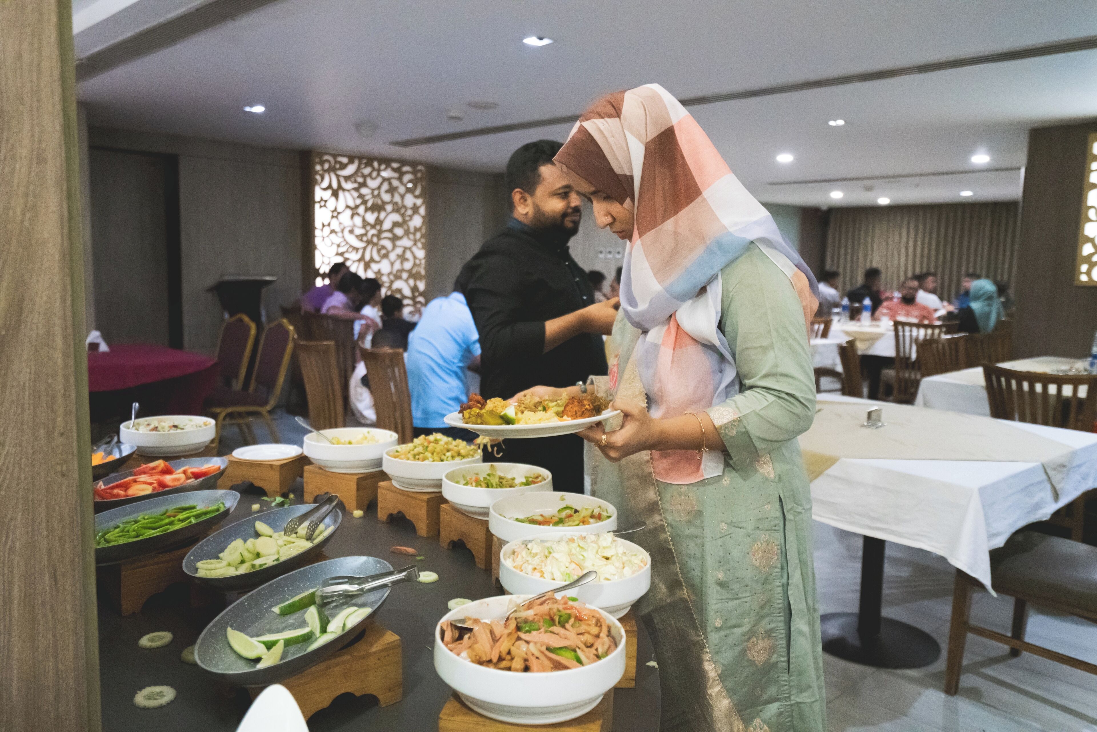 A buffet setup with various dishes and a person serving food.