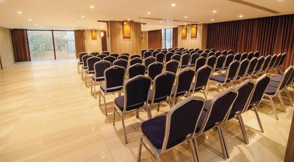 A conference room with rows of chairs, wooden floors, and large windows.