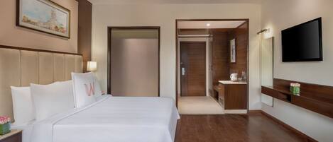 A hotel room with a large bed, a bedside table, a TV, a bathroom with a mirror, and a painting on the wall.