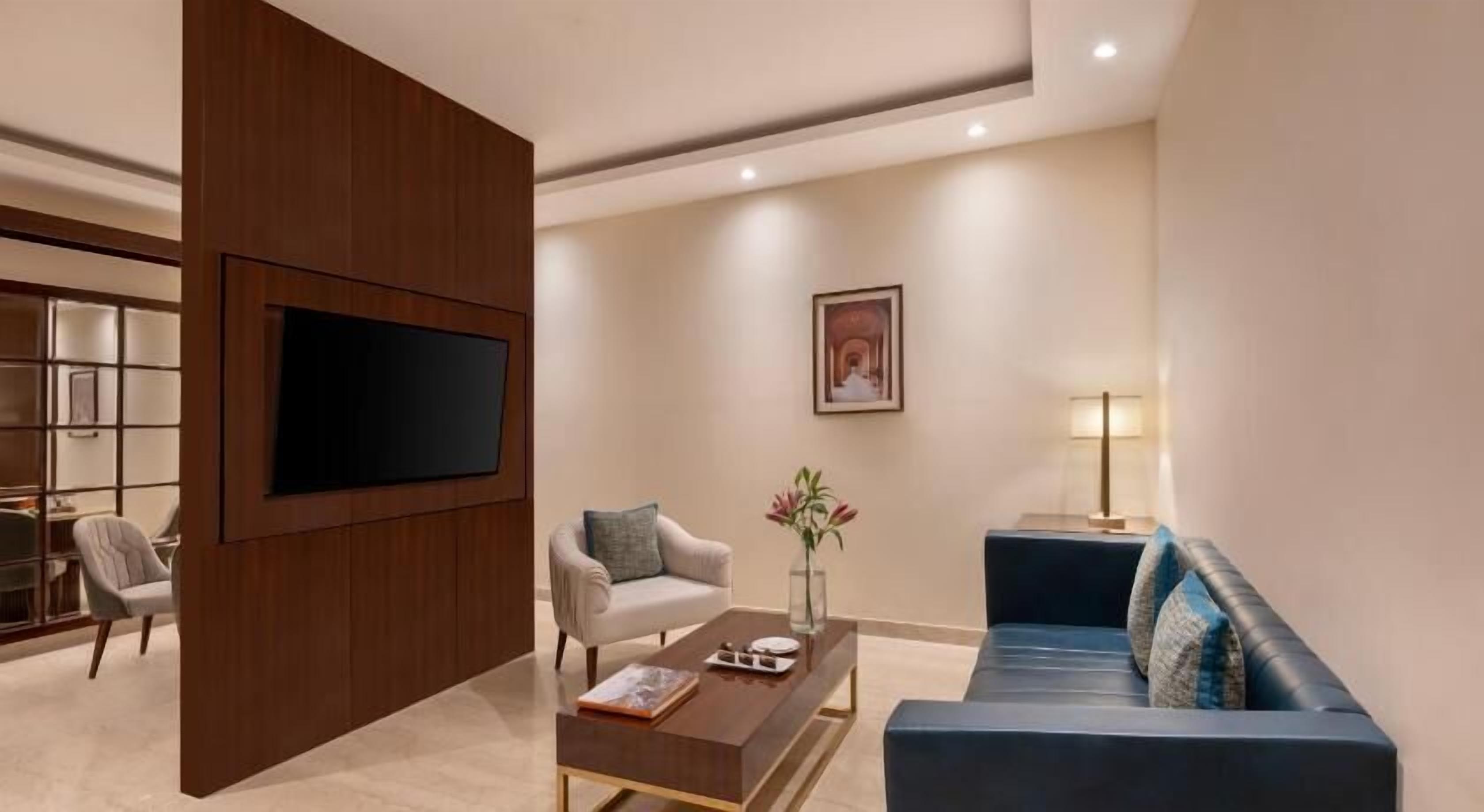 A modern living room with a flat-screen TV, a sofa, a chair, and a coffee table.
