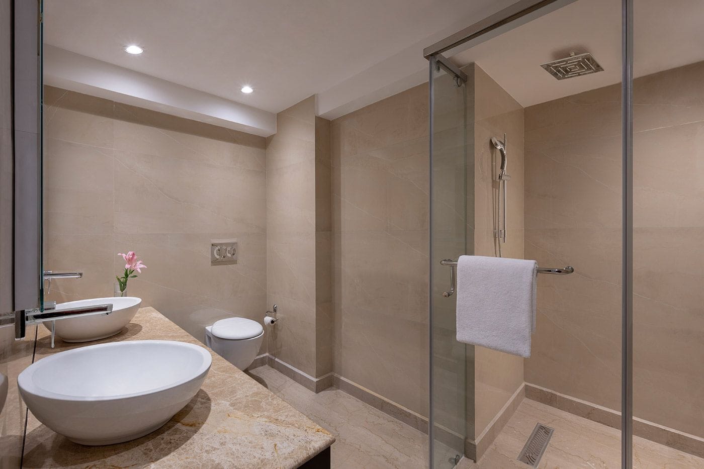 A modern bathroom with a glass-enclosed shower, a freestanding sink, and a toilet.