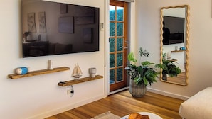 A modern living room with a flat-screen TV, wooden shelves, a round coffee table, and a large mirror. - Casa Mar - Beachside Bliss.
Sun, sand and family fun All in one place. (Carrum)