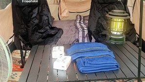 A tent with a table set up inside. There are two black bags labeled "Freehike" and a lantern on the table. - Koh Kood Good Time (Ko Kood)