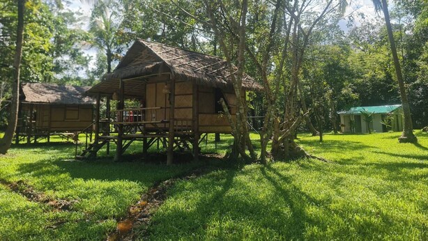 A rustic wooden structure with a thatched roof, surrounded by lush greenery and trees. - Koh Kood Good Time (Ko Kood)