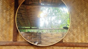 A mirror with a woven frame, a shelf with toiletries, and a woven wall. - Koh Kood Good Time (Ko Kood)