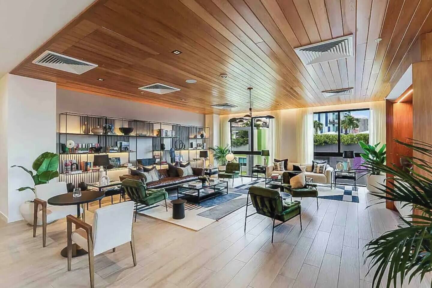 A spacious living area with a wooden ceiling, a kitchen with modern appliances, and large windows offering a view of the outdoors.