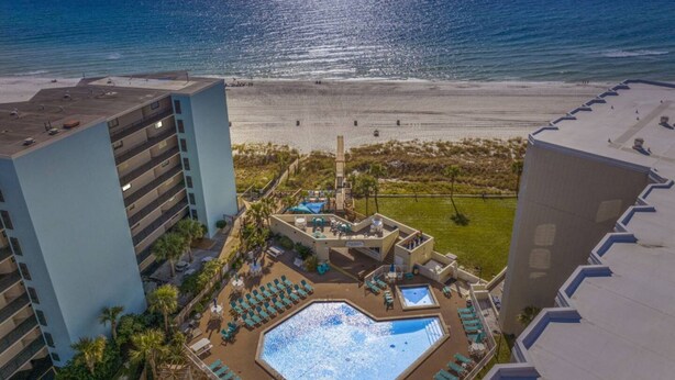 A hotel with a rooftop pool, beach view, and multiple buildings. - Beach Front Ocean Front Condo Top of the Gulf 516 (Panama City Beach)
