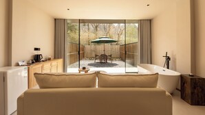 Une chambre moderne dotée d’une grande fenêtre, d’une baignoire, d’un canapé et d’un coin repas avec une table et des chaises.