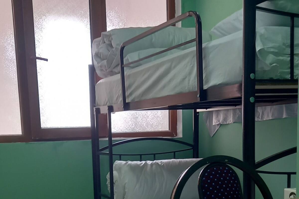 Um quarto com beliches, uma escrivaninha e um aparelho de ar condicionado.