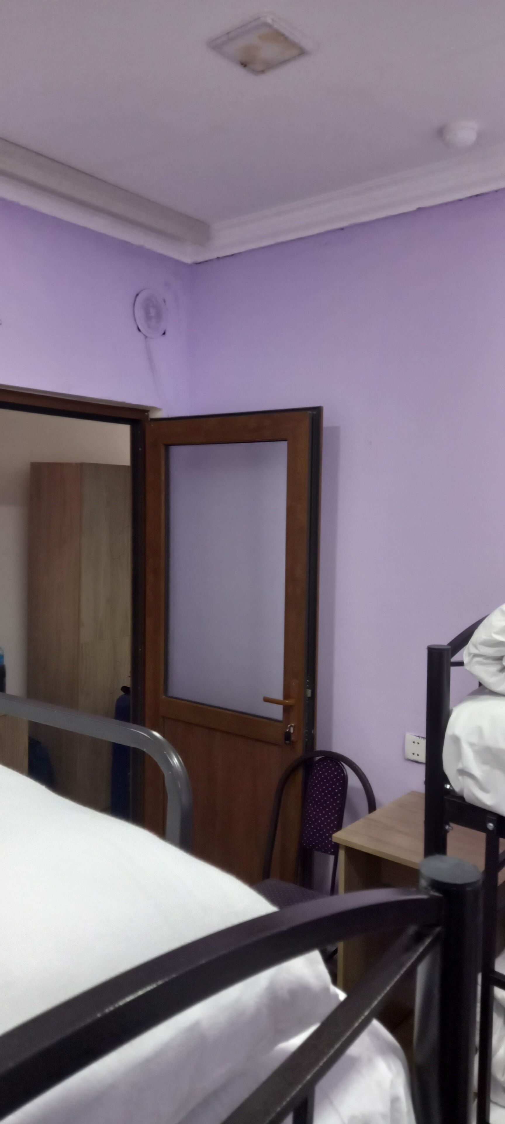 A room with a bed, a desk, a chair, and a wardrobe.