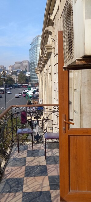 A balcony with a view of a busy street, a tiled floor, and a wooden door. - 28 may Centr City hostel (Baku)