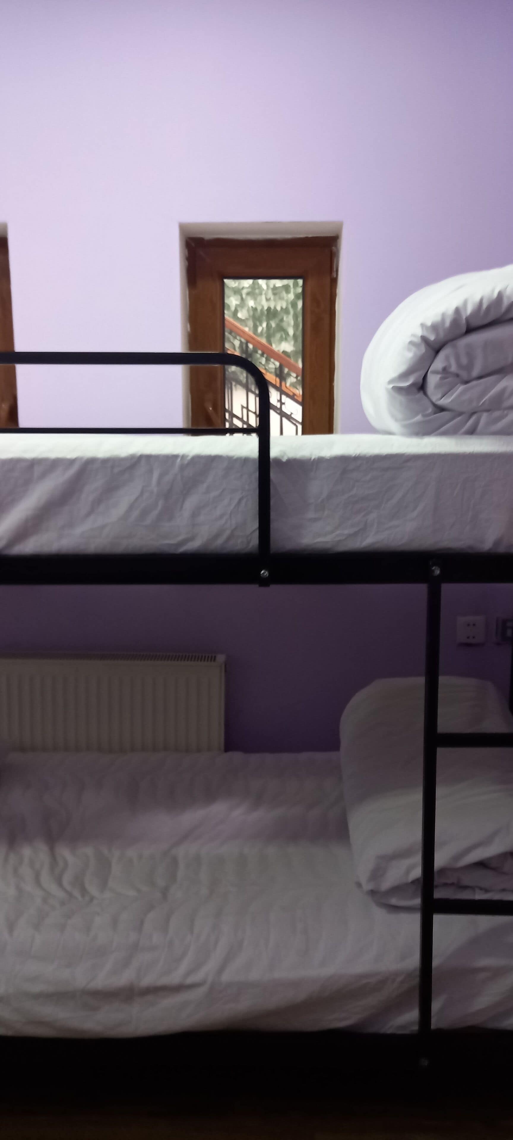 Een slaapkamer met een stapelbed, raam en radiator.