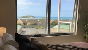 A bedroom with a large window overlooking a coastal area, a bed with pillows, and a bedside lamp. - Bayview Encounter - Sea and island views in luxury incl breakfast and linen. (Encounter Bay)