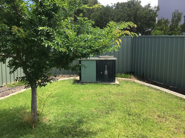 A fenced yard with a small utility shed and a tree.