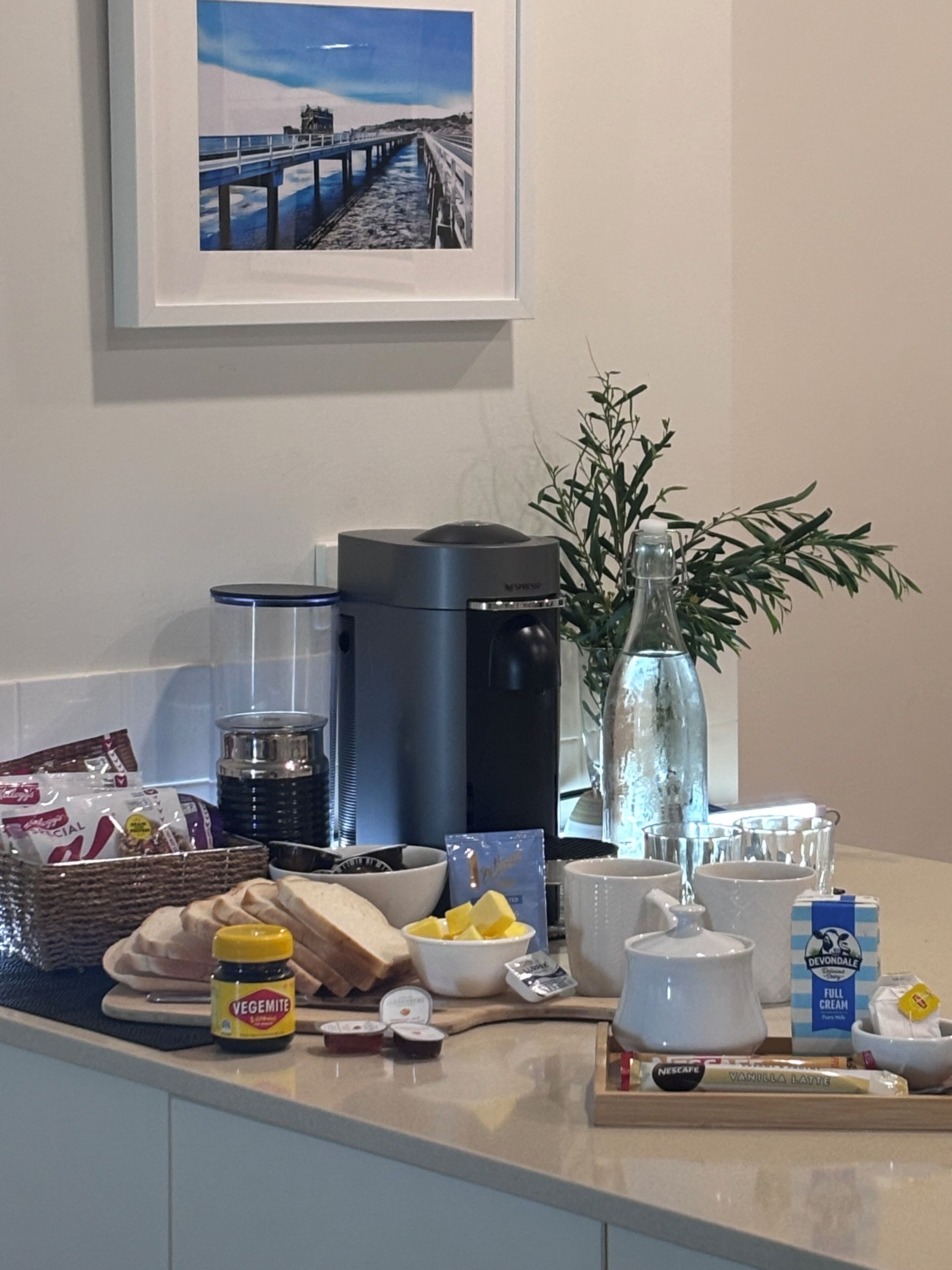 A kitchen counter with a coffee maker, a bottle of water, a plant, and various food items.