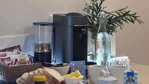 A kitchen counter with a coffee maker, a bottle of water, a plant, and various food items. - Bayview Encounter - Sea and island views in luxury incl breakfast and linen. (Encounter Bay)