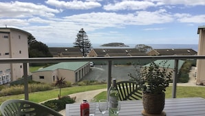 A balcony with a table, chairs, a bottle of wine, and a potted plant. - Bayview Encounter - Sea and island views in luxury incl breakfast and linen. (Encounter Bay)