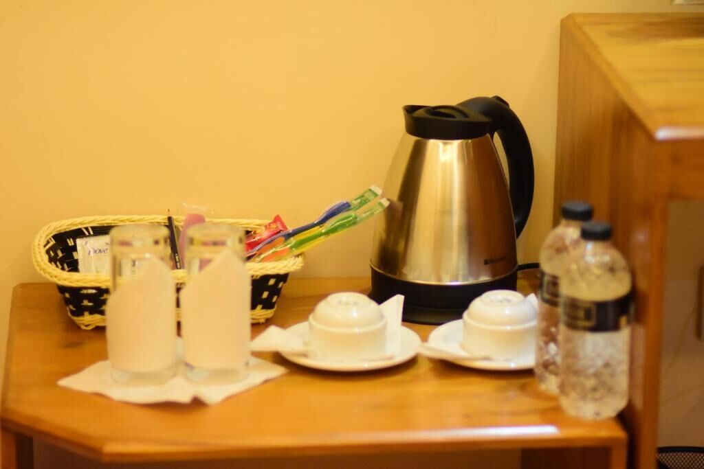 A small table with a kettle, a basket of toiletries, and two bottles of water.