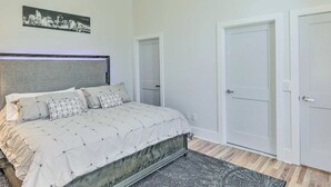 Una camera da letto con un letto, una ventola a soffitto, un quadro con una veduta urbana e due porte.
