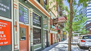 Una vista di strada con una fila di edifici, tra cui un ristorante chiamato 'Scott's Italian Restaurant' e un cartello che pubblicizza '3CDC Condos in vendita'.