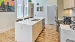 Una cucina moderna con isola centrale, elettrodomestici in acciaio inossidabile e luci a sospensione.
