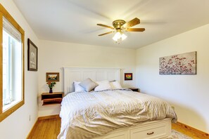 Ein Schlafzimmer mit einem Bett, Nachttischen, einem Deckenventilator und Kunstwerken an den Wänden.