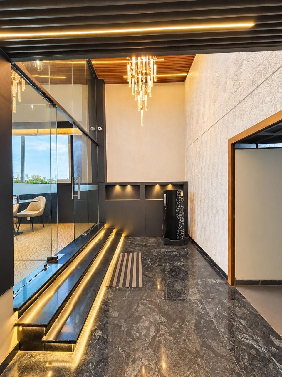 A modern interior with a glass partition, a staircase, and a black marble floor.