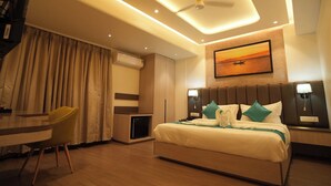 A modern hotel room with a bed, bedside lamps, a desk, and a chair. - Hotel Vedic Roots (Varanasi)